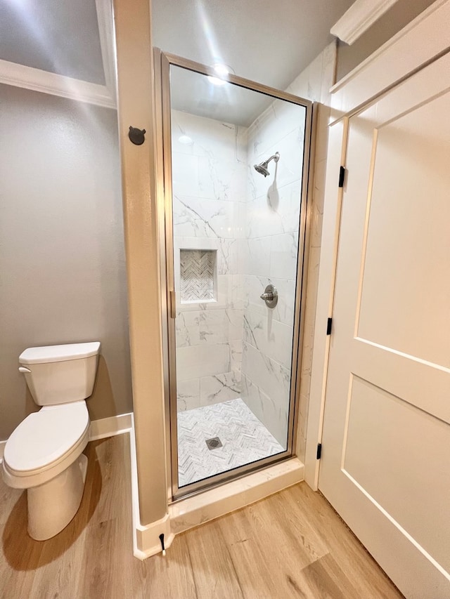 bathroom featuring hardwood / wood-style floors, a shower with shower door, and toilet