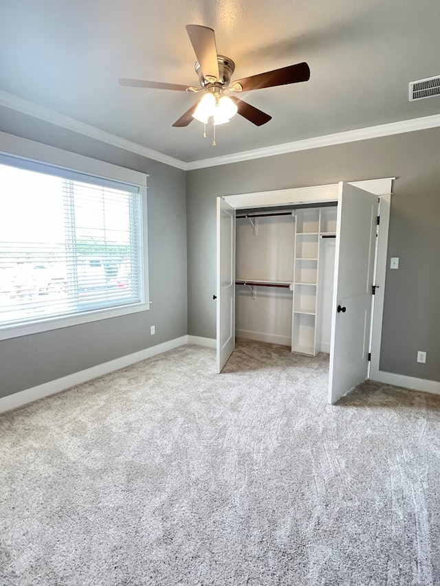 unfurnished bedroom featuring carpet floors, ornamental molding, a closet, and ceiling fan