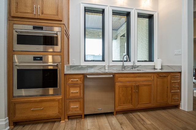 kitchen featuring sink, stainless steel double oven, and light hardwood / wood-style floors