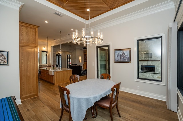 dining space featuring crown molding, a notable chandelier, dark hardwood / wood-style floors, and a raised ceiling