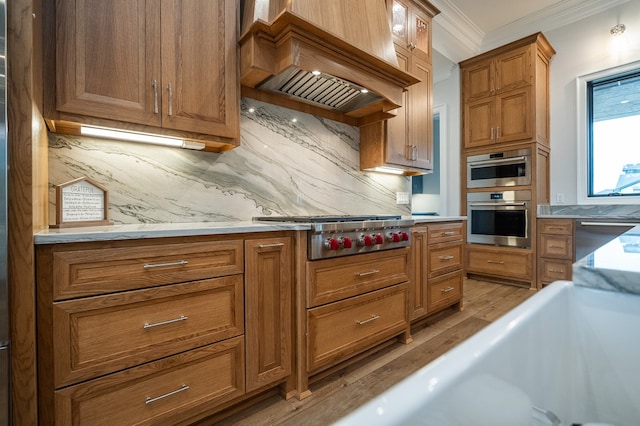 kitchen featuring backsplash, custom exhaust hood, light hardwood / wood-style floors, stainless steel appliances, and crown molding