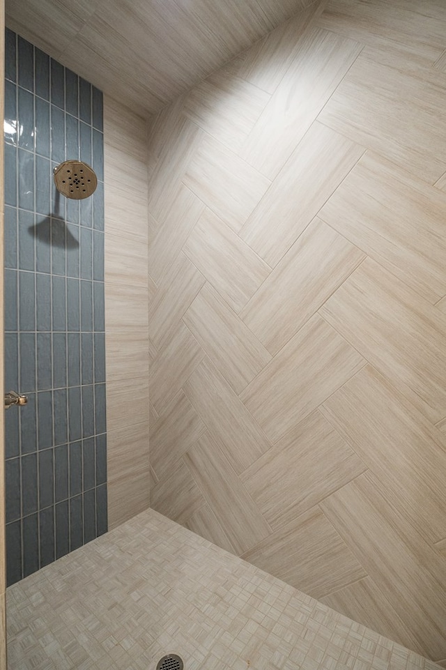 bathroom featuring a tile shower and parquet flooring