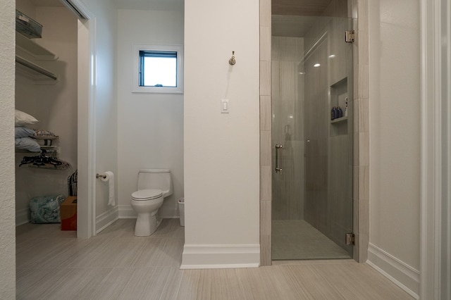 bathroom featuring a shower with door and toilet