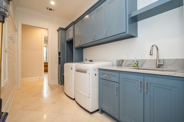 washroom featuring cabinets, ornamental molding, sink, and washing machine and clothes dryer