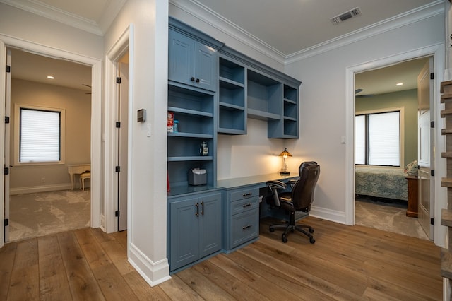 office space with ornamental molding, built in desk, and light hardwood / wood-style floors