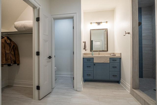 bathroom featuring vanity, toilet, and tiled shower