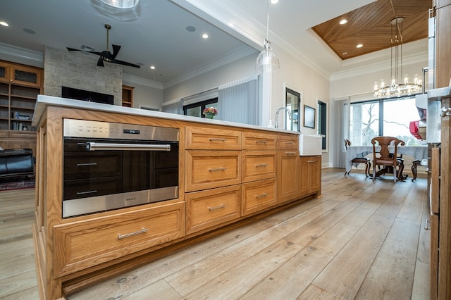 kitchen featuring pendant lighting, oven, ornamental molding, a notable chandelier, and light wood-type flooring