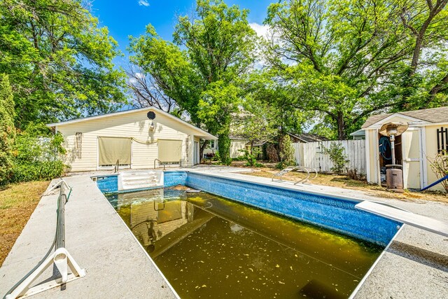 view of swimming pool with a storage unit and a diving board