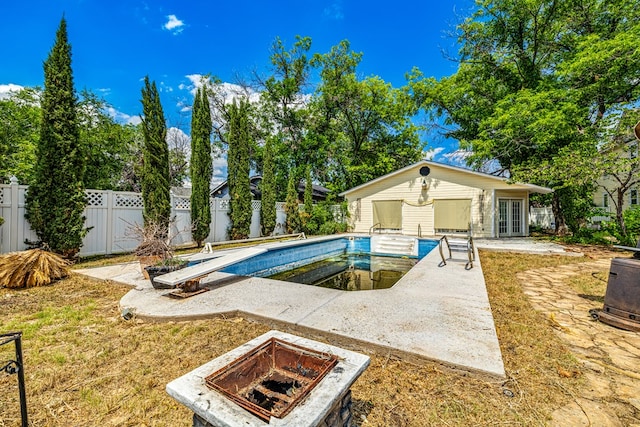 view of pool featuring an outbuilding, an outdoor fire pit, a diving board, and a patio