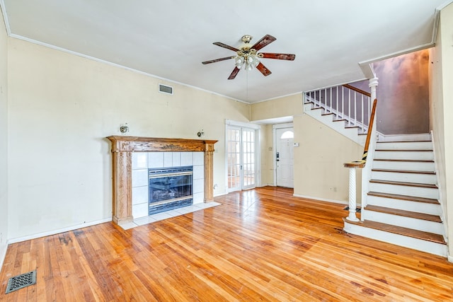 unfurnished living room with a tiled fireplace, crown molding, light hardwood / wood-style flooring, and ceiling fan