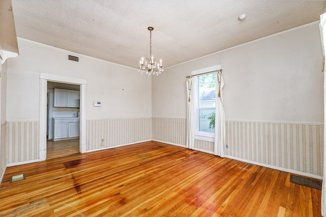 empty room with hardwood / wood-style floors, crown molding, a chandelier, and a textured ceiling