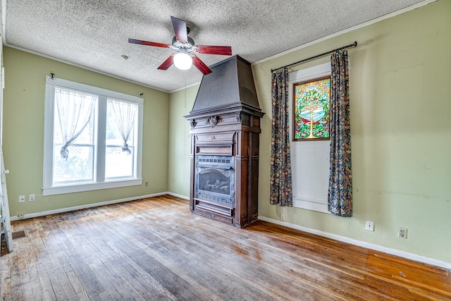 unfurnished living room featuring a fireplace, ceiling fan, light hardwood / wood-style floors, crown molding, and a textured ceiling