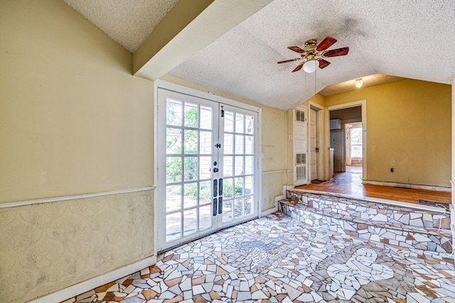 doorway to outside with french doors, ceiling fan, vaulted ceiling, and a textured ceiling