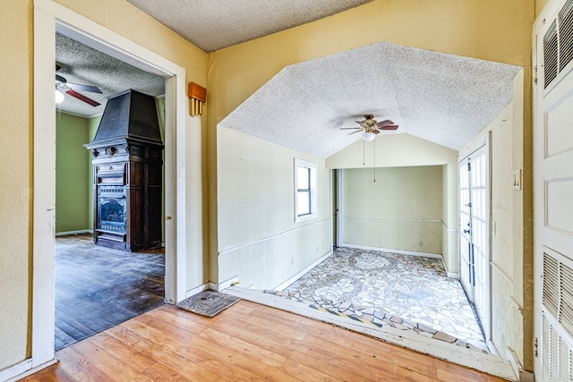 interior space featuring wood-type flooring, lofted ceiling, and a textured ceiling