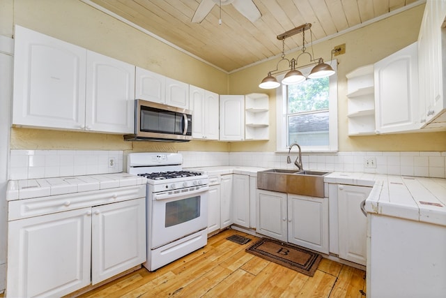 kitchen featuring tile countertops, white cabinetry, sink, wood ceiling, and white gas stove