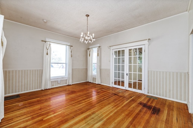 empty room featuring hardwood / wood-style floors, a textured ceiling, and a notable chandelier