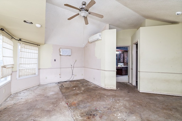 spare room featuring an AC wall unit, lofted ceiling, and a textured ceiling