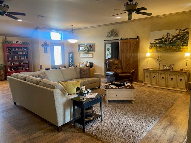 11725 Little Sorrel Trl, San Angelo, TX 76904 - living area featuring a ceiling fan, a barn door, wood finished floors, and ornamental molding