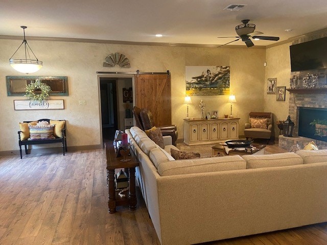 11725 Little Sorrel Trl, San Angelo, TX 76904 - living room with wood finished floors, ceiling fan, a barn door, baseboards, and crown molding