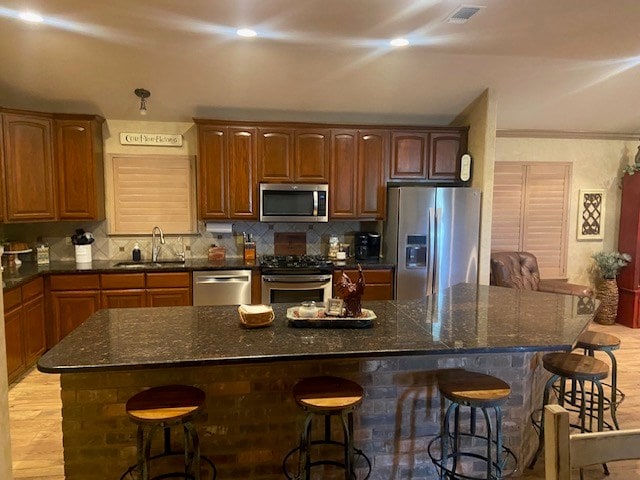 11725 Little Sorrel Trl, San Angelo, TX 76904 - kitchen with appliances with stainless steel finishes, a sink, a kitchen breakfast bar, decorative backsplash, and dark stone countertops