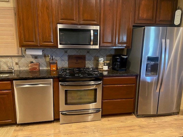 11725 Little Sorrel Trl, San Angelo, TX 76904 - kitchen featuring appliances with stainless steel finishes, backsplash, a sink, dark stone counters, and light wood finished floors