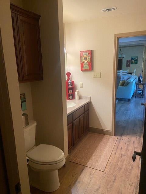 11725 Little Sorrel Trl, San Angelo, TX 76904 - half bathroom featuring wood finished floors, vanity, toilet, and baseboards