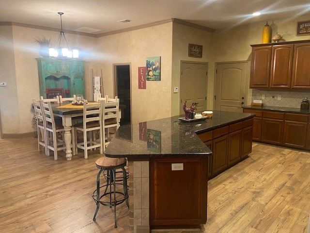 11725 Little Sorrel Trl, San Angelo, TX 76904 - kitchen featuring light wood-style floors, ornamental molding, a center island, a chandelier, and decorative backsplash