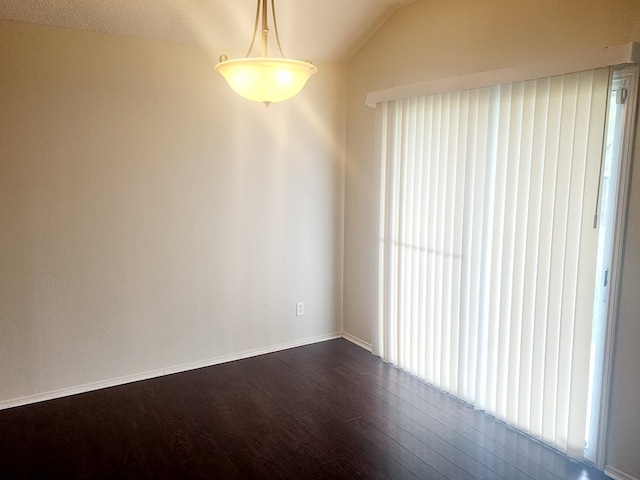unfurnished room featuring lofted ceiling, baseboards, and dark wood-type flooring