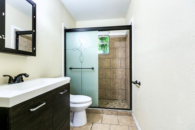 2818 Abilene St, San Angelo, TX 76901 - full bathroom featuring toilet, a stall shower, tile patterned floors, a textured wall, and vanity