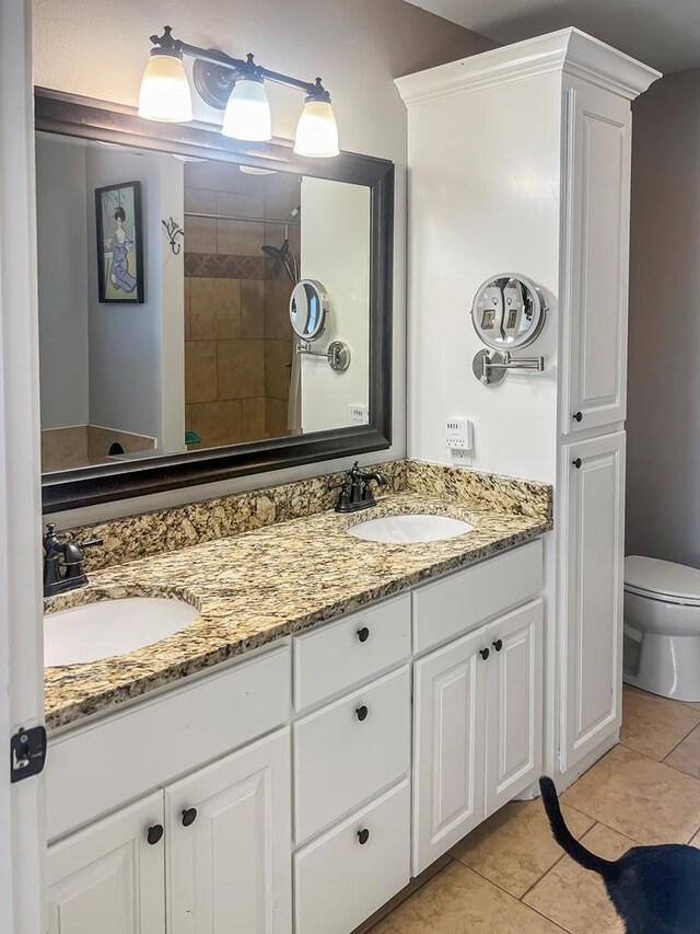 bathroom featuring tiled shower, vanity, toilet, and tile patterned flooring