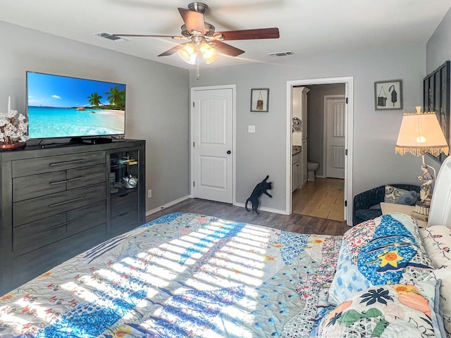 bedroom with dark wood-type flooring, ceiling fan, and ensuite bath