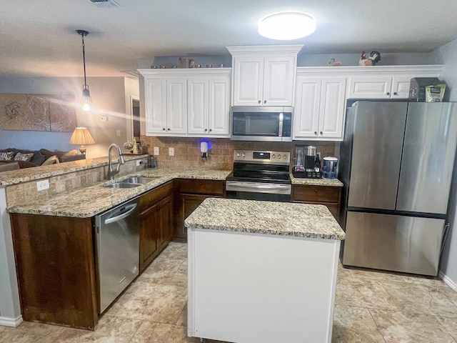 kitchen with appliances with stainless steel finishes, pendant lighting, sink, white cabinets, and decorative backsplash