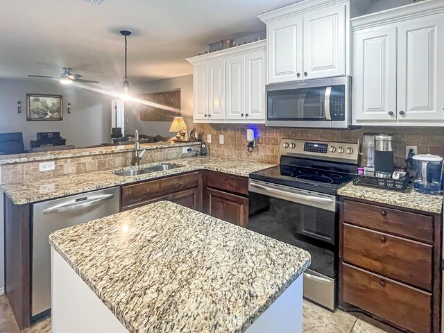 kitchen featuring sink, appliances with stainless steel finishes, backsplash, white cabinets, and a kitchen island