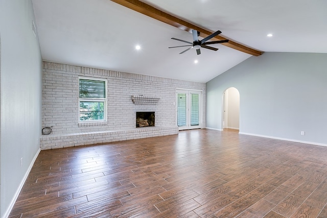 3868 Honeysuckle Ln, San Angelo, TX 76904 - unfurnished living room featuring a ceiling fan, wood finished floors, healthy amount of natural light, arched walkways, and brick wall