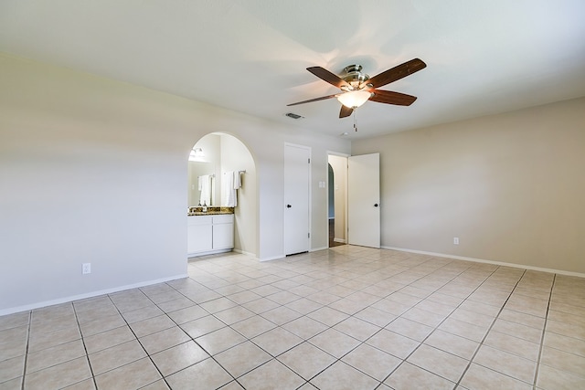 3868 Honeysuckle Ln, San Angelo, TX 76904 - spare room featuring a ceiling fan, arched walkways, light tile patterned floors, and baseboards