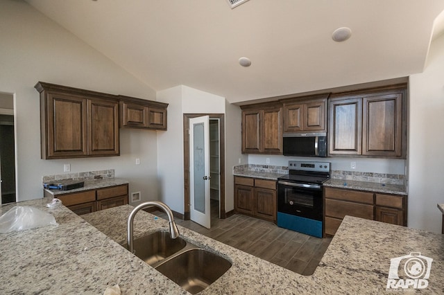 kitchen with wood finish floors, range with electric stovetop, a sink, light stone countertops, and stainless steel microwave