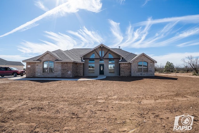 view of front of house featuring a shingled roof and brick siding