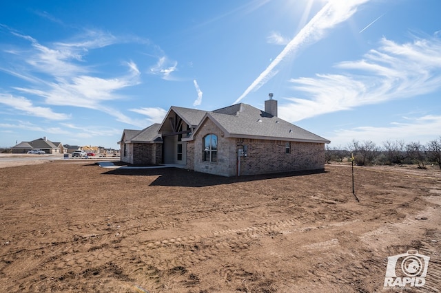 exterior space with stone siding, a chimney, and brick siding