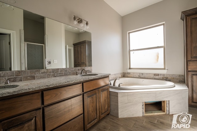 bathroom with a bath, a stall shower, double vanity, and a sink