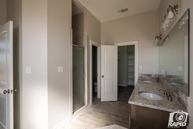 full bath with toilet, a stall shower, visible vents, and a sink