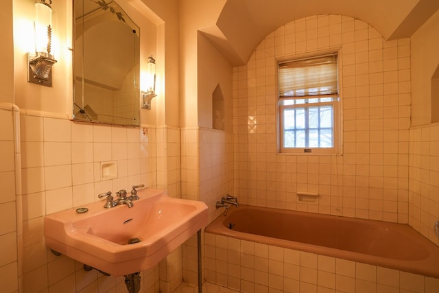 bathroom with tile walls, sink, and tiled tub