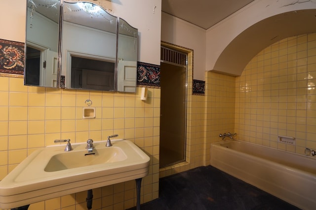 bathroom featuring sink, a bathtub, and tile walls