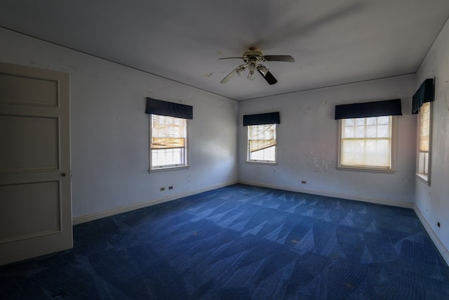 carpeted spare room featuring plenty of natural light and ceiling fan