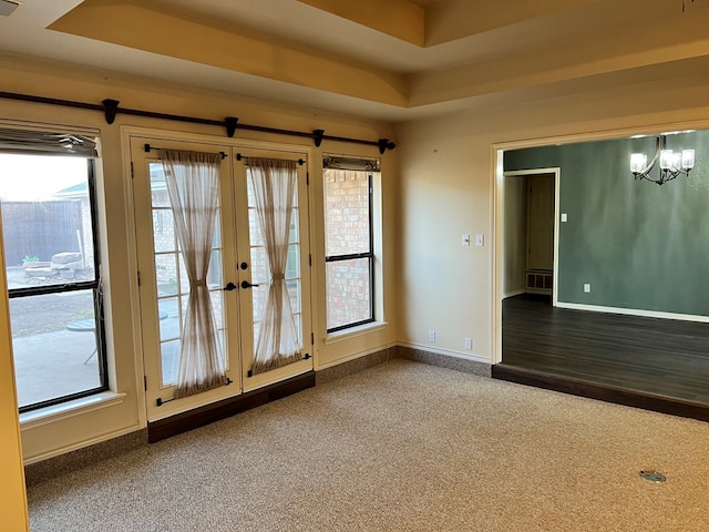 empty room featuring a notable chandelier, french doors, baseboards, and carpet floors