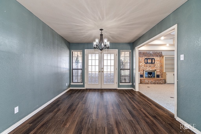 3413 Sequoia Cir, San Angelo, TX 76904 - unfurnished dining area with a textured wall, a chandelier, baseboards, dark wood-type flooring, and french doors