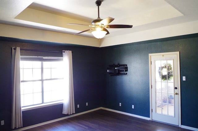 unfurnished room with wood finished floors, a ceiling fan, baseboards, and a raised ceiling