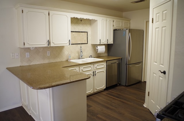 kitchen with white cabinets, a peninsula, stainless steel appliances, and a sink