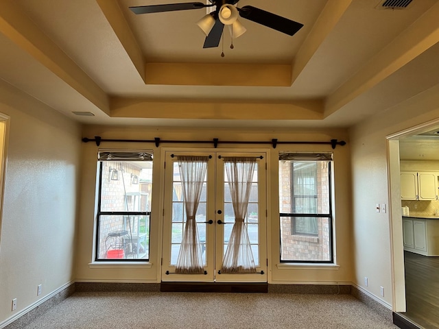 entryway featuring a raised ceiling, plenty of natural light, and ceiling fan