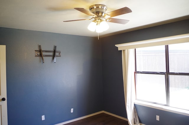 spare room with baseboards, dark wood finished floors, and a ceiling fan