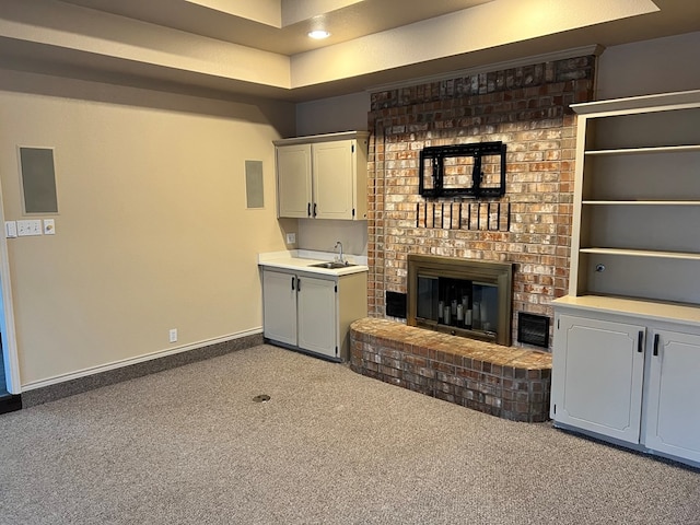 unfurnished living room featuring visible vents, a brick fireplace, baseboards, carpet flooring, and a sink